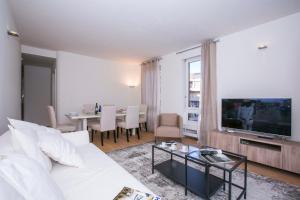 ein Wohnzimmer mit einem weißen Sofa und einem TV in der Unterkunft Lugano Motta - Happy Rentals in Lugano