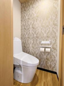 a white toilet in a bathroom with wallpaper at Mezon Akihabara Guest House in Tokyo