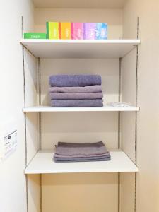 a closet with white shelves with purple towels at Mezon Akihabara Guest House in Tokyo