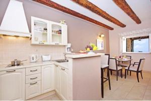 a kitchen with white cabinets and a dining table at Luxury Panorama Villa Dia in Brsečine +33 photos