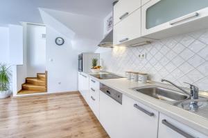 una cucina con mobili bianchi e un lavandino di Pool House Edita - Happy Rentals a Bribir