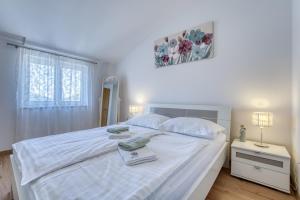 una camera da letto con un letto bianco con due asciugamani sopra di Pool House Edita - Happy Rentals a Bribir