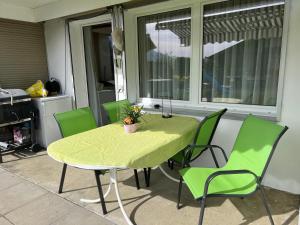 a green table and chairs on a patio with a window at Ferienwohnung Sonnenseite Brienz in Brienz