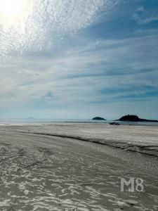 uma praia vazia com pegadas na areia em Cantinho do Mar Pousada em Bertioga