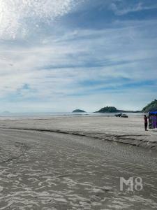 una persona parada en una playa con una cometa en Cantinho do Mar Pousada, en Bertioga