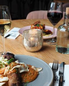 einen Tisch mit einem Teller mit Essen und Gläsern Wein in der Unterkunft Hotel 't Vertrek in Boxmeer