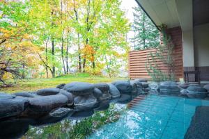 a swimming pool with a stone wall next to a house at Morinoyu Hotel Hanakagura in Asahikawa