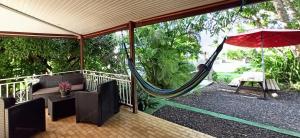 a porch with a hammock and a table and chairs at Studio a Sainte Anne a 350 m de la plage avec piscine partagee jardin clos et wifi in Sainte-Anne