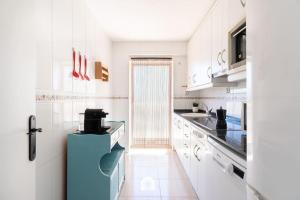 uma cozinha com armários brancos e um frigorífico azul em Mediterranean Way - Hawai em Salou