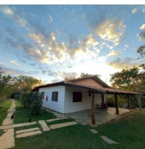 a small white house with a roof on the grass at Pousada Rio das Almas in Pirenópolis