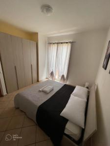 una camera da letto con un letto con cuscini bianchi e una finestra di Casa Vacanza Accetta a Trappeto