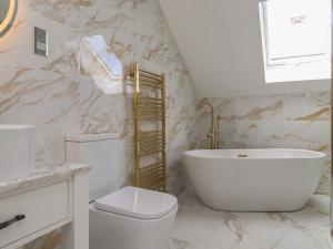 a bathroom with a tub and a toilet and a sink at Blue Bay Villa in Holyhead +47 photos