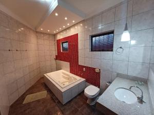 a bathroom with a tub and a toilet and a sink at HOTEL TABARANA in Ubarana