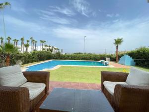 eine Terrasse mit 2 Stühlen und einem Pool in der Unterkunft Villa Marina Smir avec piscine in Tétouan