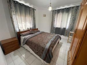 a bedroom with a bed and two windows with curtains at Villa Marina Smir avec piscine in Tetouan