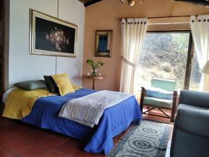 a bedroom with a bed and a chair and a window at Cabaña los cerezos in Ubaté