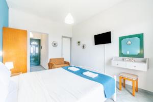 a white bedroom with a bed and a tv at Spyridoula Studio 3 in Paleokastritsa
