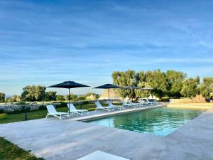 a group of chairs and umbrellas next to a pool at Masseria Celeste in Fasano