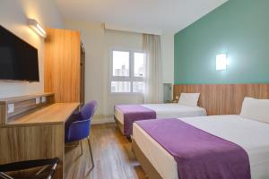 um quarto de hotel com duas camas e uma televisão de ecrã plano em Go Inn Cambuí Campinas em Campinas