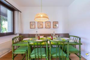 a dining room table with green chairs and a chandelier at Villa Calella - Happy Rentals in Magliaso
