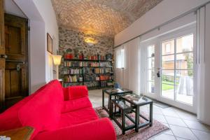 Casa Tamè في ميليده: غرفة معيشة مع أريكة حمراء ورف كتاب