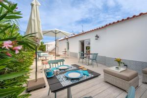 eine Terrasse mit einem Tisch, Stühlen und einem Sonnenschirm in der Unterkunft Quinta das Piteiras Turismo Rural in Silves