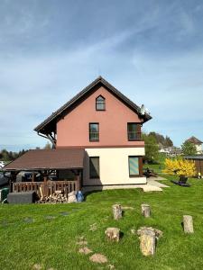 a large house with a yard with logs in front of it at Apartmány Na Rozcestí in Lomnice nad Popelkou