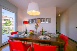 La Maison du Bonheur - Happy Rentals في Aldesago: غرفة طعام مع طاولة وكراسي حمراء