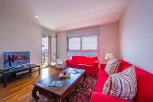 La Maison du Bonheur - Happy Rentals في Aldesago: غرفة معيشة مع أريكة حمراء وطاولة