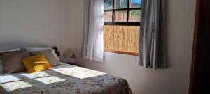 a bed with a yellow pillow and a window at Chalé na Montanha in Cunha