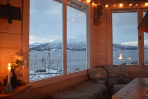 a living room with a couch in front of a large window at Aurora panorama 2nd floor in Laksvatn
