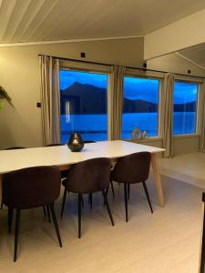 a dining room table with chairs and a large window at Aurora panorama 2nd floor in Laksvatn