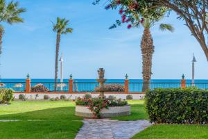 a park with palm trees and a fountain and the ocean at Rincón Playa, terraza y piscina in Rincón de la Victoria +32 photos