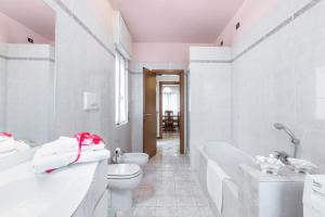 a white bathroom with a tub and a toilet and a sink at Casa Lucia - Iseo Lake View - by HOST4U in Lovere