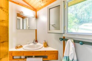 a bathroom with a sink and a mirror and a window at Camping LA SERRE in Aigues-Vives