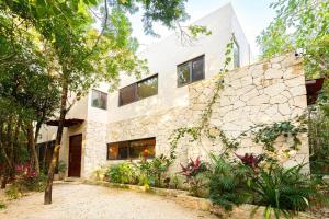 a house with a stone wall and trees at * Dream Villa on Private Cenote 10min to Beach in Akumal