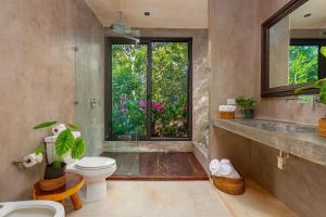 a bathroom with a toilet and a large window at * Dream Villa on Private Cenote 10min to Beach in Akumal