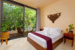 * Dream Villa on Private Cenote 10min to Beach في أكومال: غرفة نوم بسرير ونافذة كبيرة