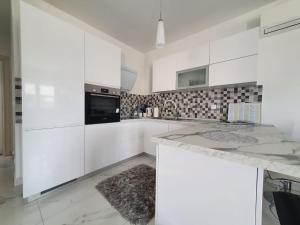 una cocina blanca con armarios blancos y un aparato negro en Apartman Sunce, en Kaštela