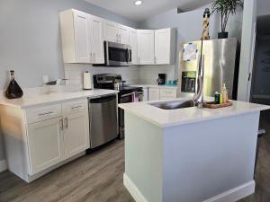 a kitchen with white cabinets and a stainless steel refrigerator at Redfish - Updated & Roomy 1.5 Mi to Beach Full Kitchen W&D in Bonita Springs
