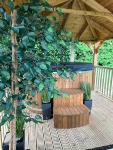 a wooden gazebo with a tree on a deck at Southwell Retreat Glamping Pods in Southwell