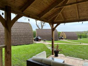 a patio with a wooden pergola and a yard at Southwell Retreat Glamping Pods in Southwell