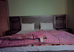 Al Sadiq Guest House في مورى: سرير عليه بطانية منقوشة