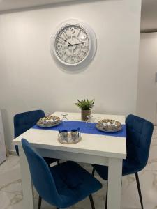 uma mesa branca com cadeiras azuis e um relógio na parede em magica Home Cannizzaro em Catânia
