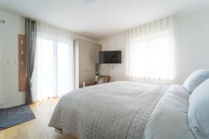 a white bedroom with a bed and a television at Lake Paradise in Brissago