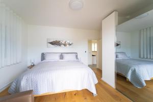 two beds in a bedroom with white walls and wood floors at Lake Paradise in Brissago