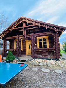 a log cabin with a ping pong table in front of it at Rönk Vendégház in Tiszaroff