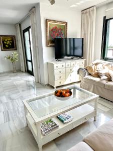 ein Wohnzimmer mit einem Couchtisch aus Glas und einem TV in der Unterkunft Penthouse Benalmadena Arroyo de la Miel centro in Benalmádena