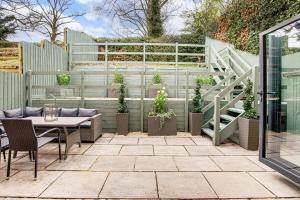 a patio with a table and chairs and a fence with plants at Foxglove House in Loughborough