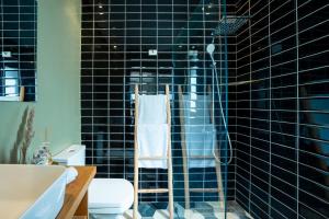 a black tiled bathroom with a shower and a toilet at dar al walidine in Marrakesh +16 photos